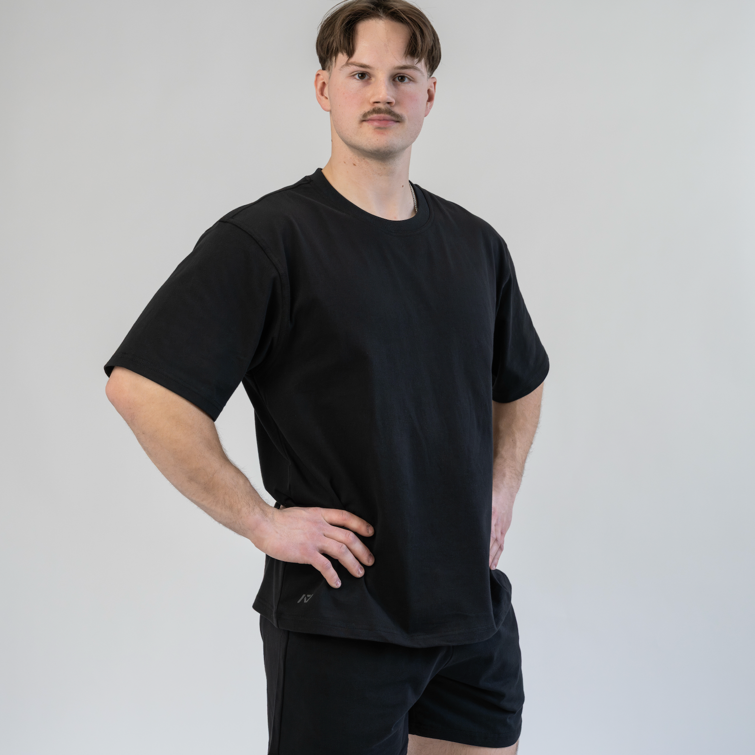 Man wearing a black t-shirt and shorts against a plain background