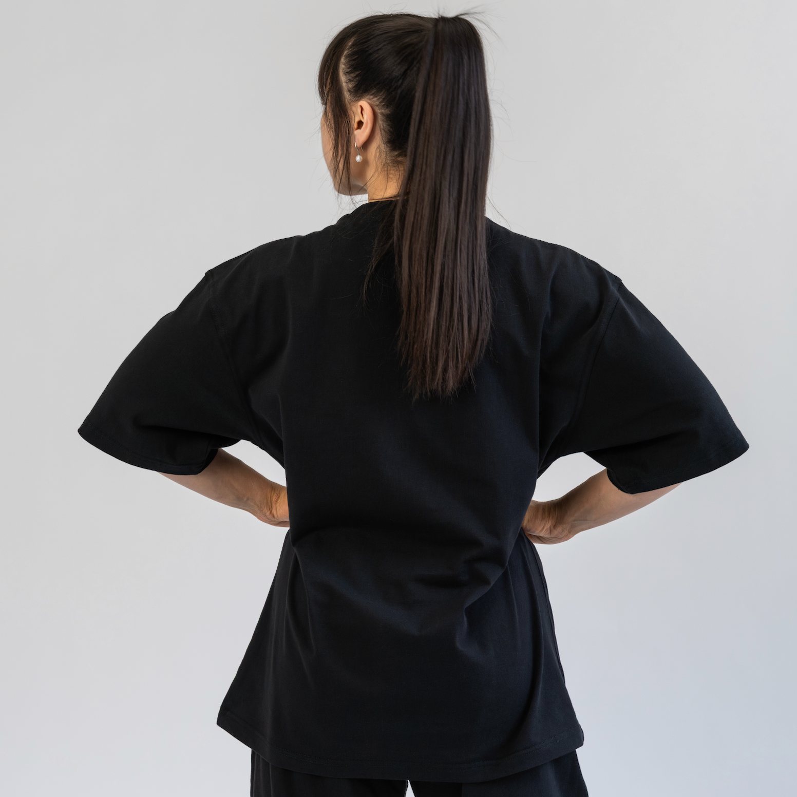 Person wearing a black outfit with wide sleeves and pants on a plain background