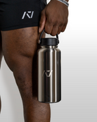 Person holding a stainless steel water bottle with a brand logo on a plain background