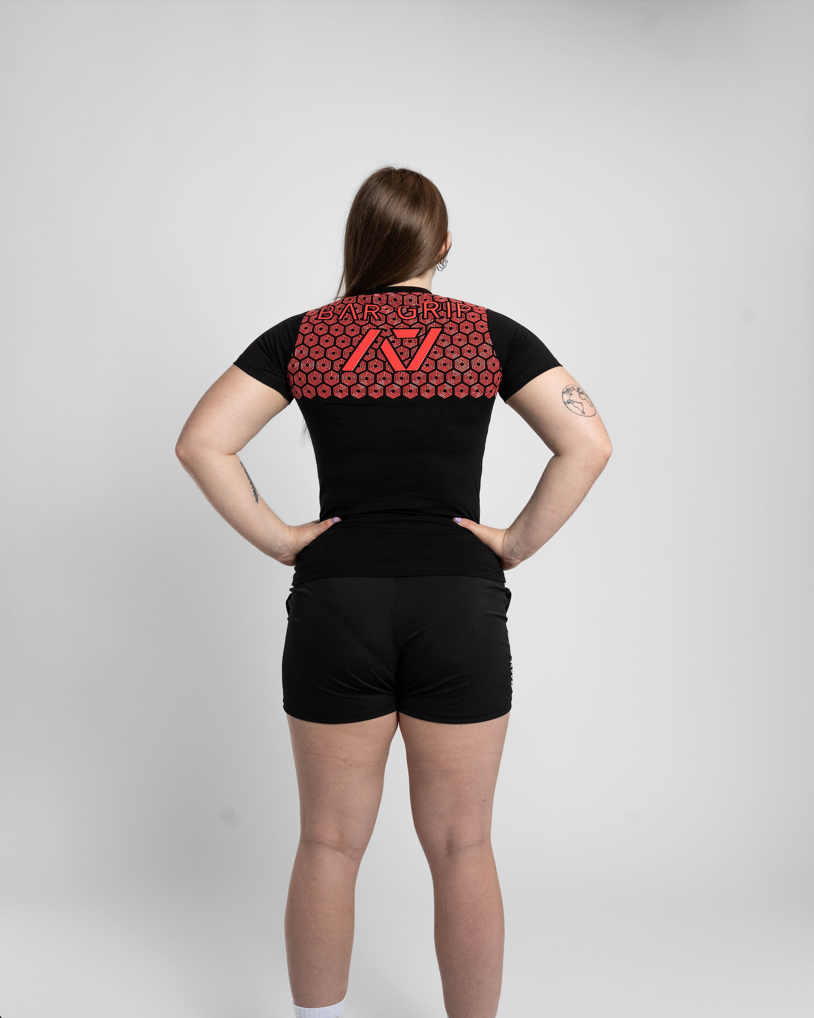 Person wearing a black t-shirt with a red bar grip on the back against a white background