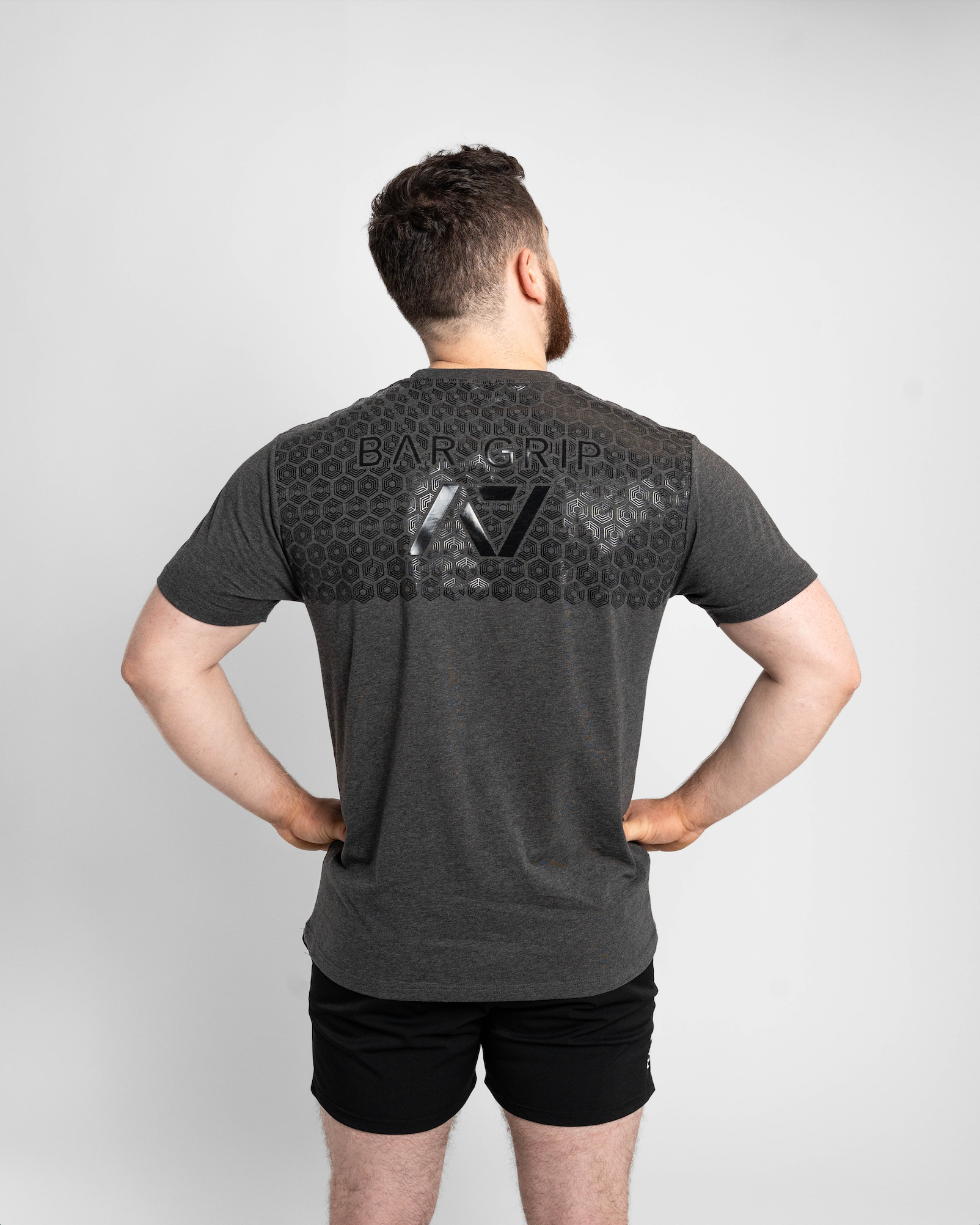 Man wearing a gray t-shirt with a7 bar grip on the back against a white background
