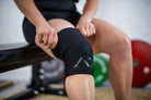 Athlete wearing A7 Stealth Stiff CONE Knee Sleeves during squat, demonstrating fit and support.